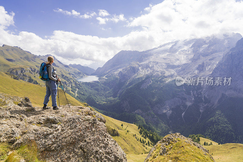 意大利北部Dolomites的Viel dal Pan小路上，一位老妇人正在欣赏美丽的Fedaia湖和Marmolada湖。